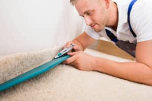 Professional carpet fitter installing new carpet in a living room as part of a flooring renovation.